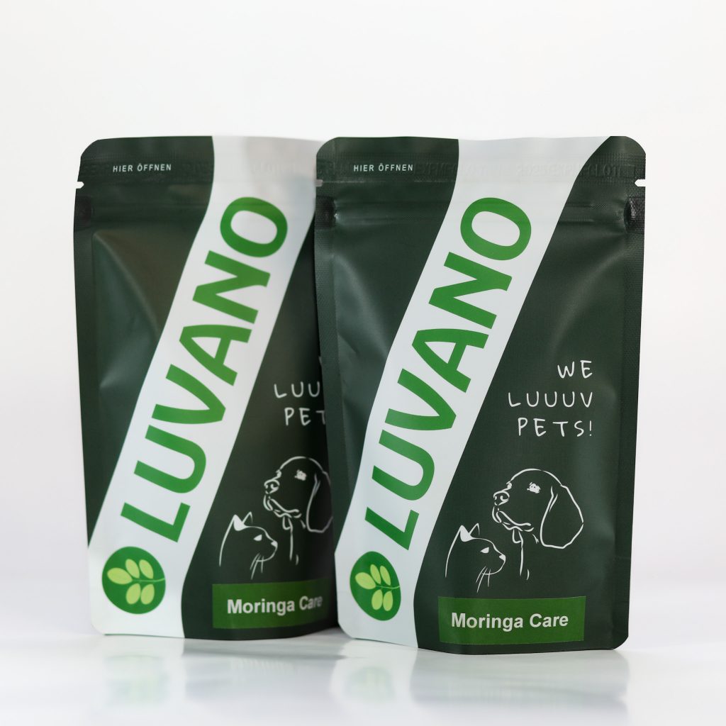 Zwei Luvano Moringa Care Pulver Standbeutel für Hunde vor hellem Hintergrund