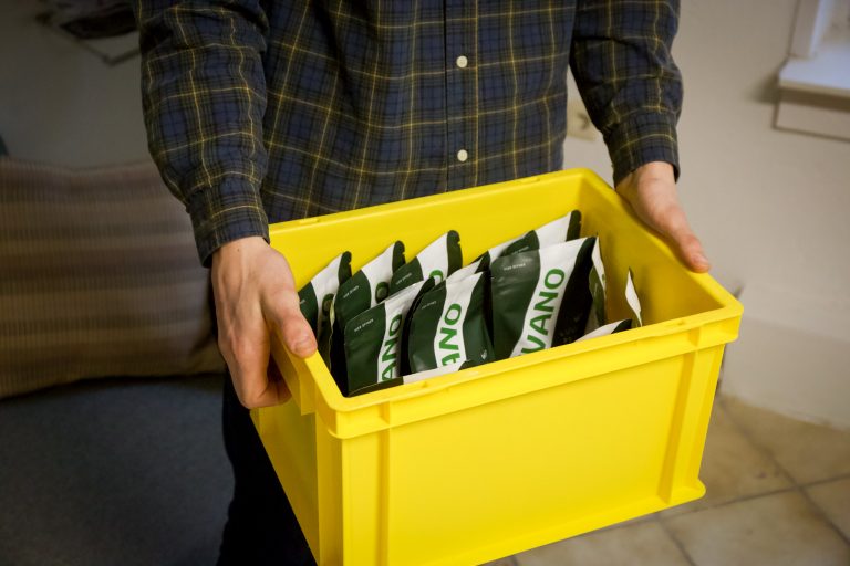 Mitarbeiter hält Kiste mit verpackten Nahrungsergänzungsmitteln für Hunde – Versand und Lagerung hochwertiger Produkte