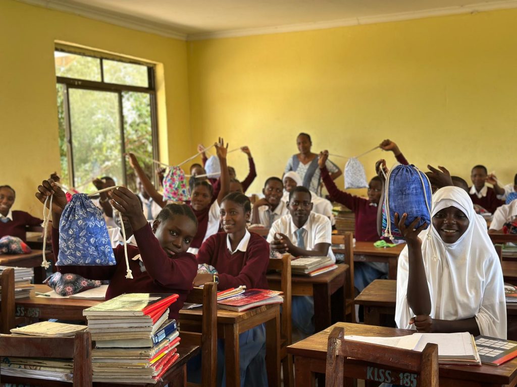 Schülerinnen und Schüler halten Taschen im Klassenzimmer – Bildungsprojekt und soziale Unterstützung