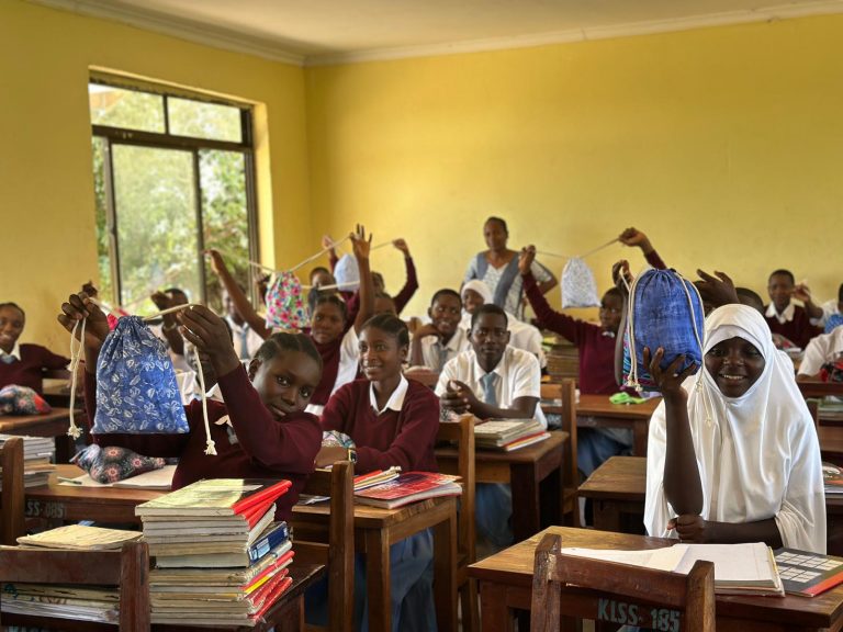 Schülerinnen und Schüler halten Taschen im Klassenzimmer – Bildungsprojekt und soziale Unterstützung